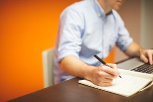 man writing on book
